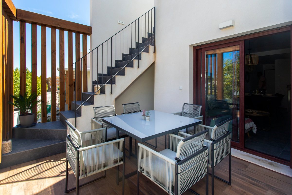 Balcony with a dining table and the private stairs up to the roof terrace, next to the living-room sliding door