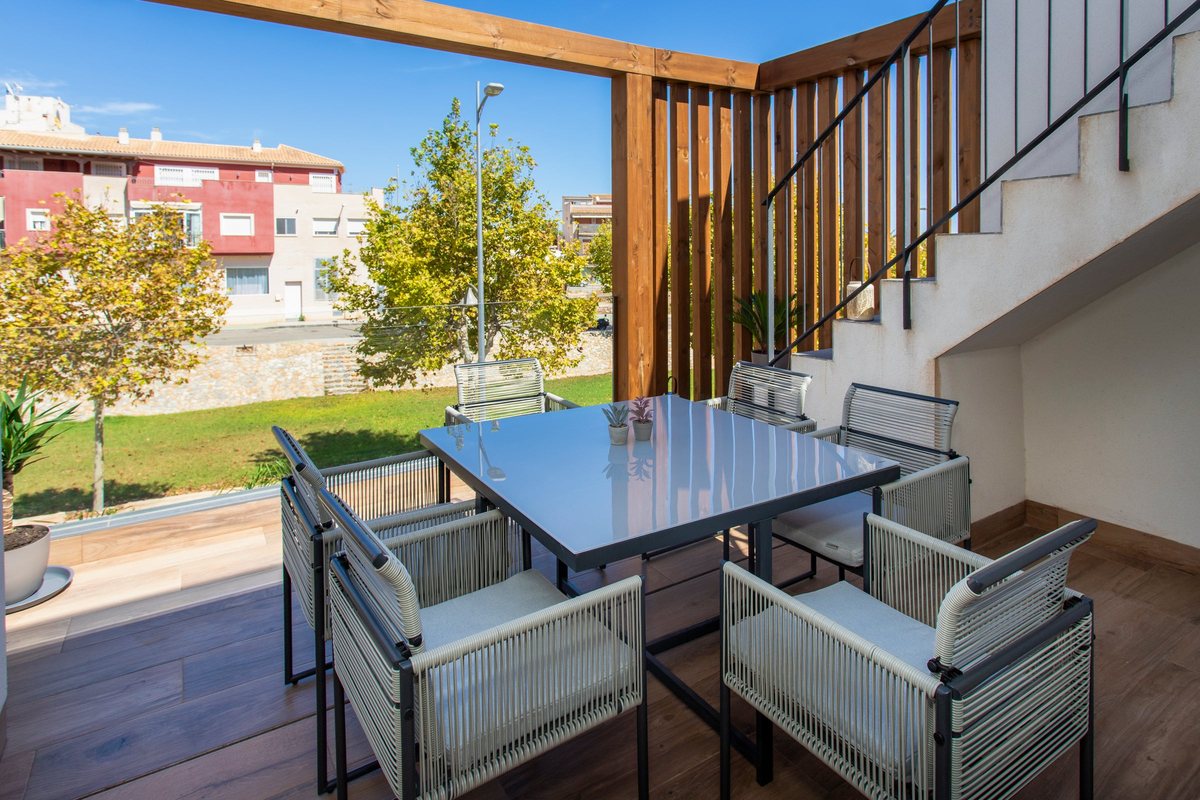 Dining table on the balcony behind wooden slats, looking out over the green strip along the street