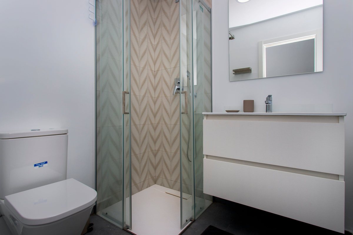 Second bathroom with a shower enclosure, zigzag-patterned tiles and a vanity unit