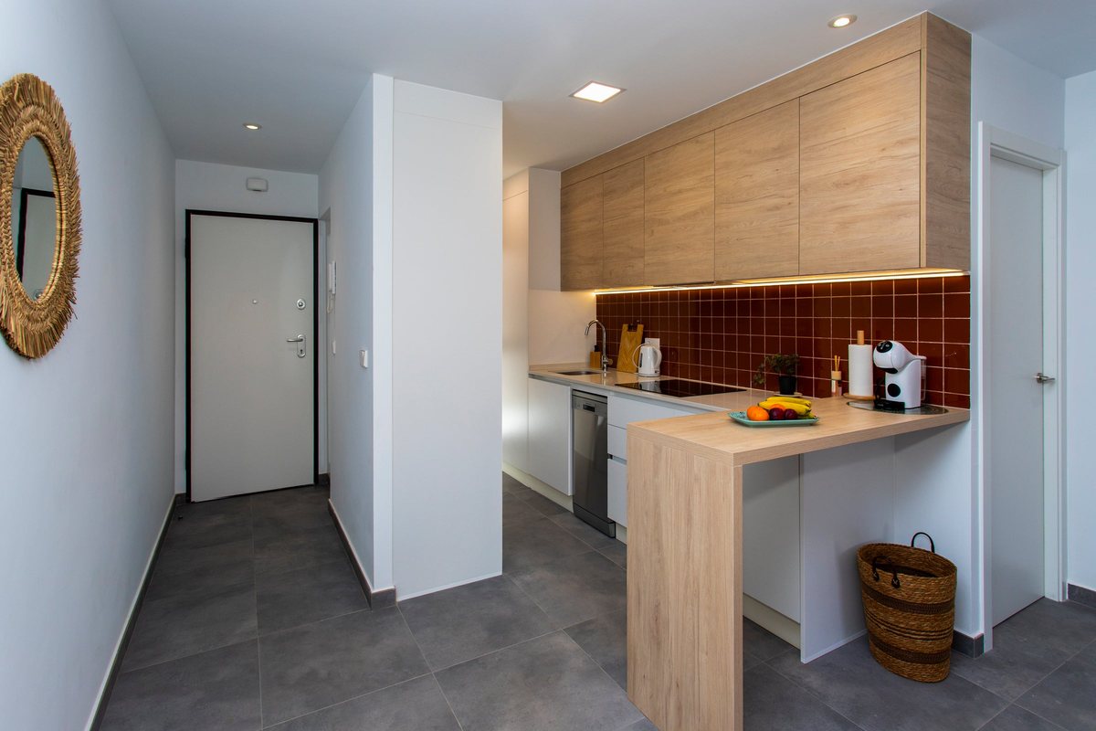 Entrance hall with the front door and the kitchen with a coffee machine and a bowl of fruit on the counter