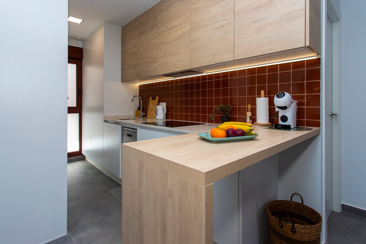 Kitchen with wooden wall cupboards, terracotta tiles and a breakfast bar