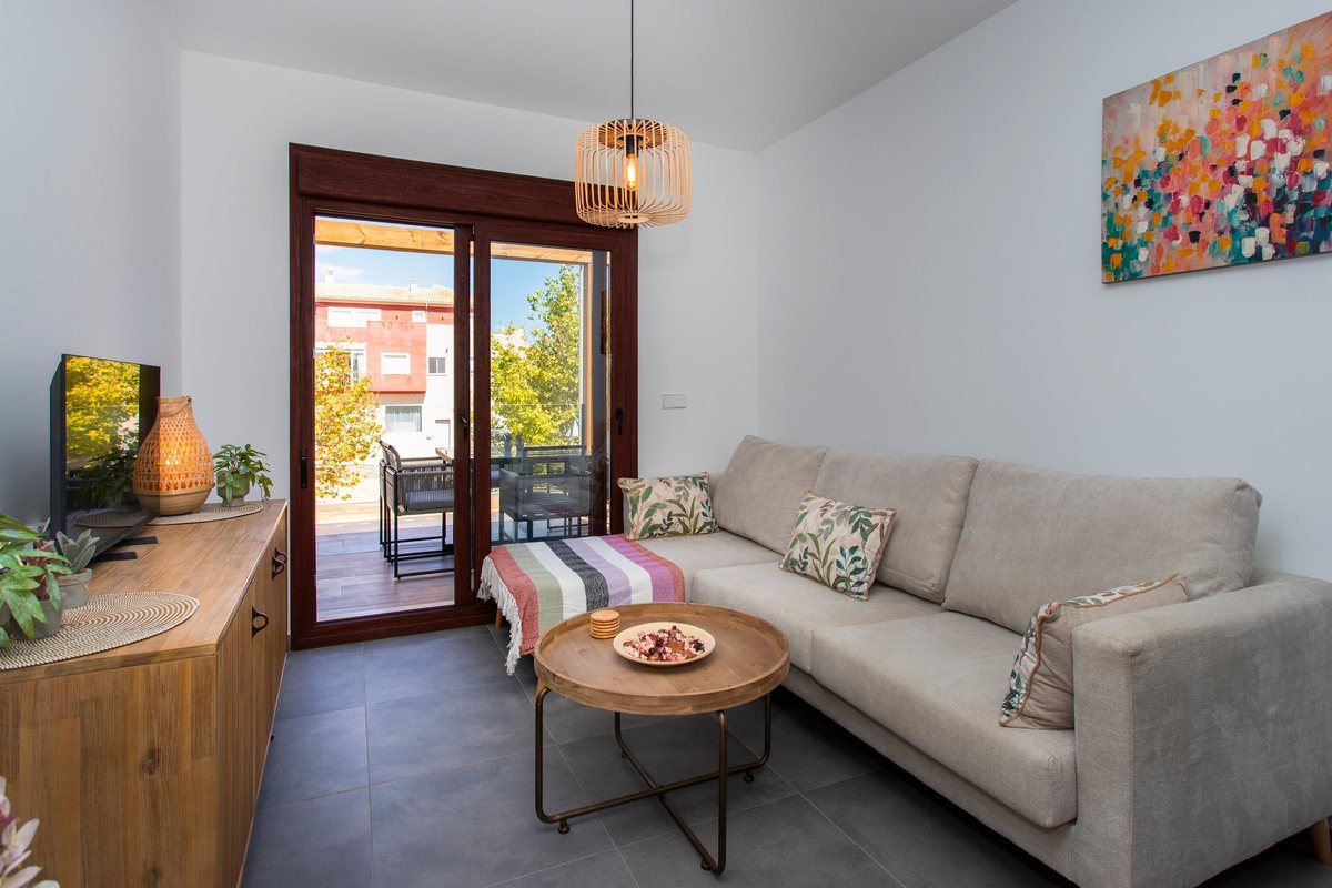 Seating area with sofa, cushions and a round coffee table by the balcony door