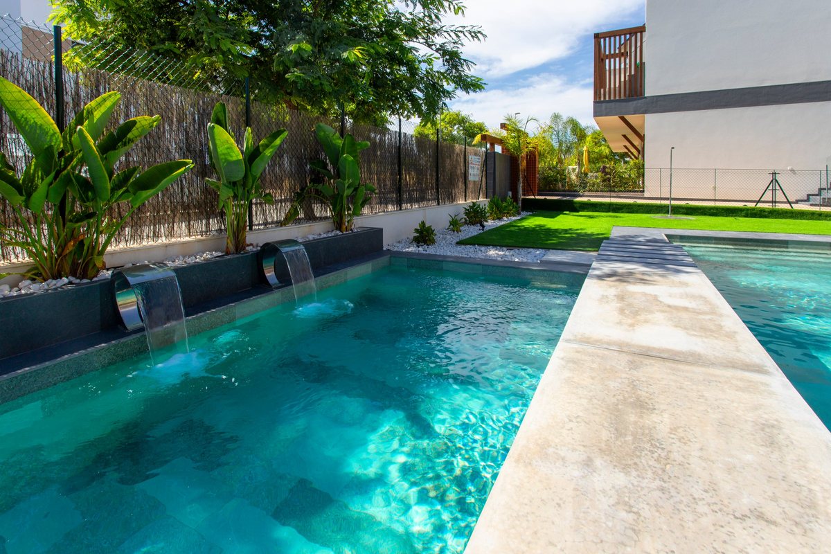 Long pool with water spouts and tropical plants