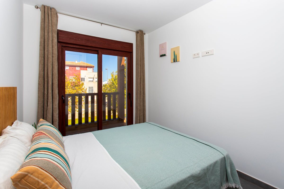 Double bed with cushions by the balcony door of the main bedroom