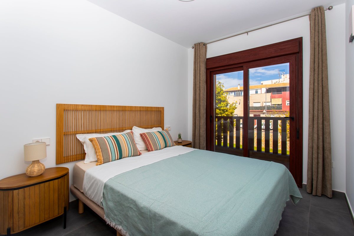 Main bedroom with a double bed, wooden headboard and a sliding door to the balcony