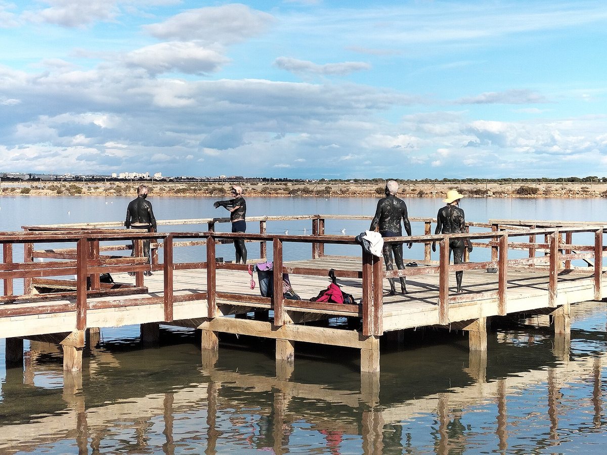 Visitors covered in mud on the jetty of the Lo Pagán mud baths
