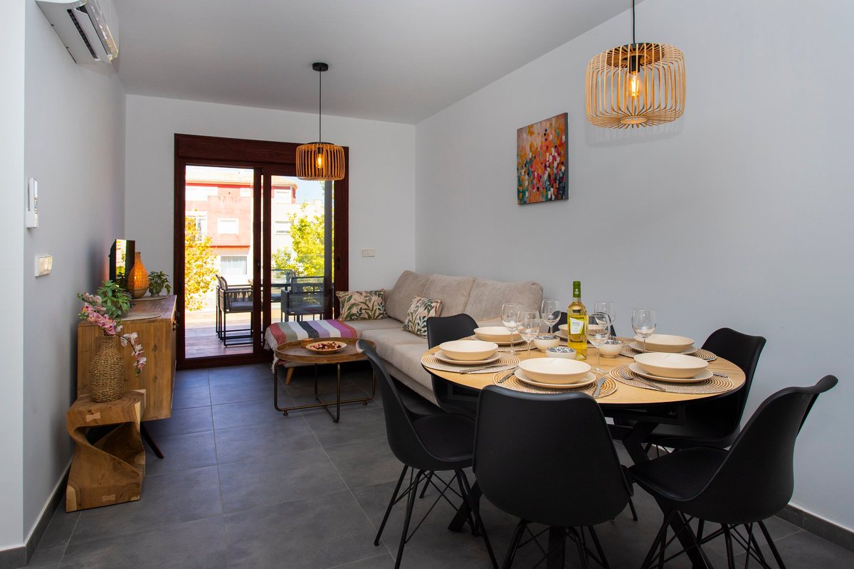 Open-plan living and dining area with the laid table, the sofa and the balcony door