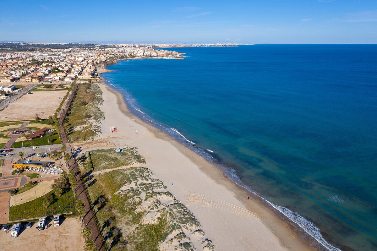 Aerial view of the long Las Higuericas beach with its dunes and wooden boardwalk