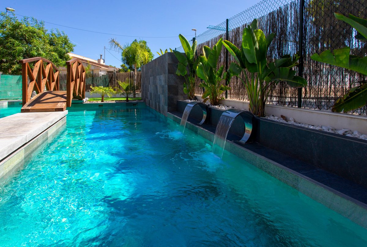 Pool with water spouts, the bridge and palm trees