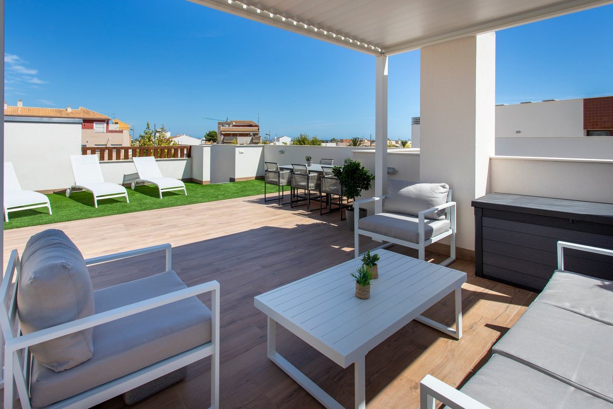 Private roof terrace of Penthouse Pilar with a lounge set, sunbeds on artificial grass and a dining table in the sun