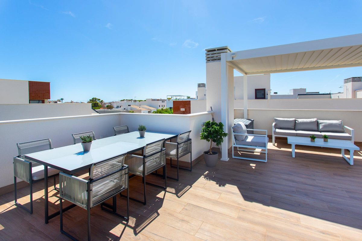 Dining table for six on the roof terrace, with the lounge corner under the pergola behind it