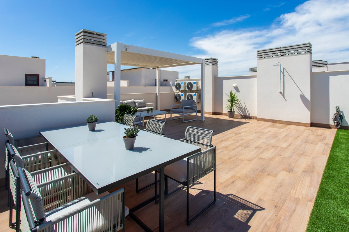 Outdoor shower on the roof-terrace wall, next to the dining table and a strip of artificial grass