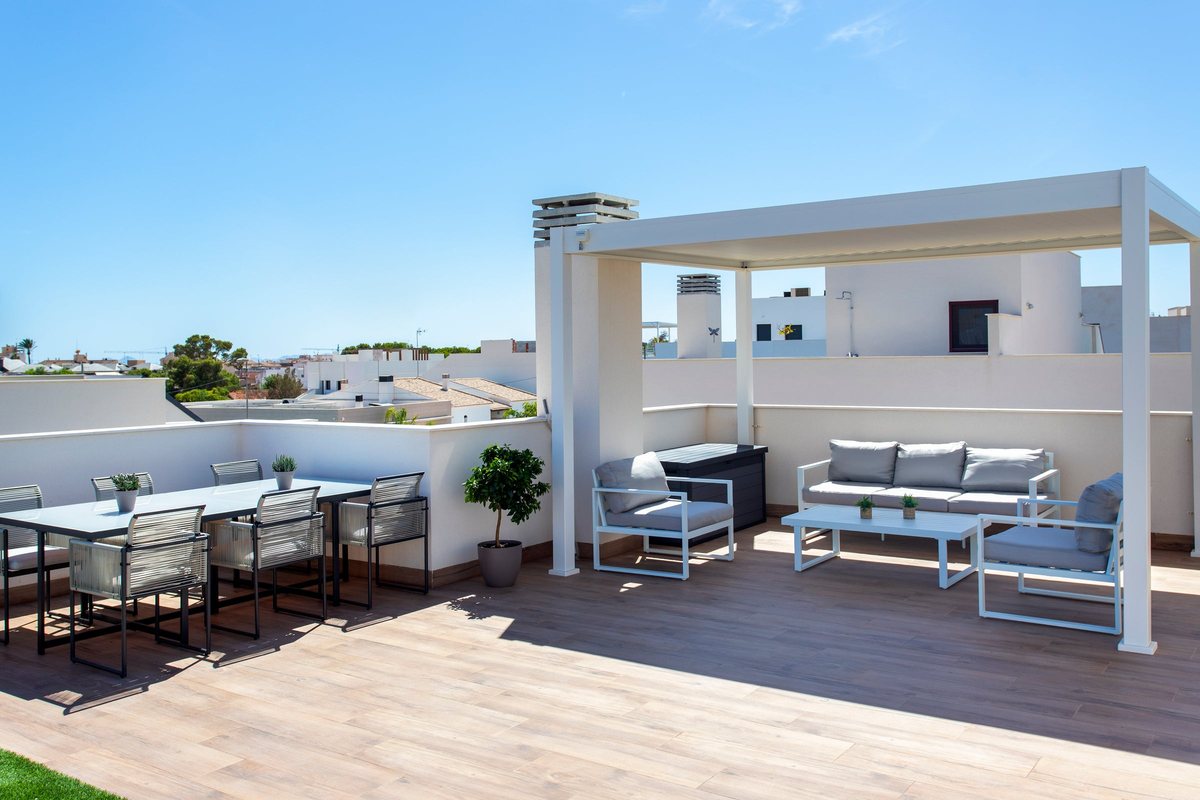 Overview of the sunny roof terrace: dining table, lounge set and pergola