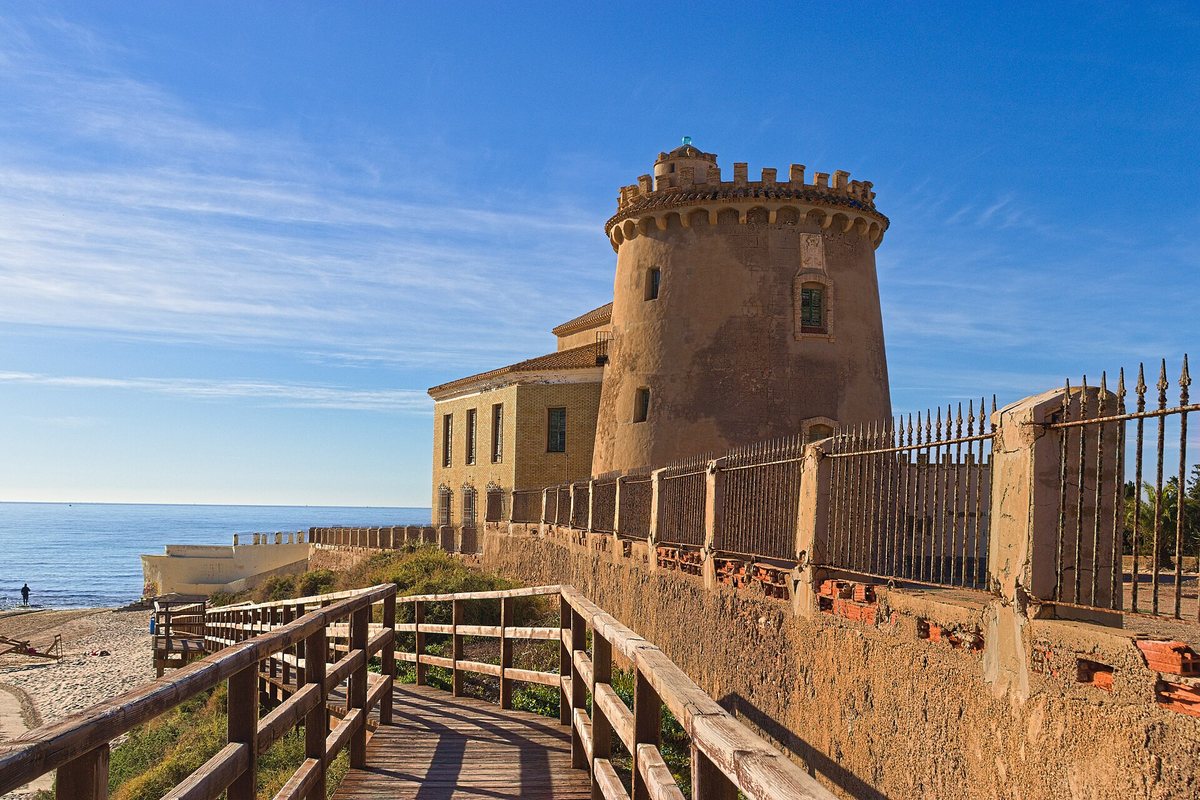 The round watchtower of Torre de la Horadada seen from the wooden boardwalk to the beach