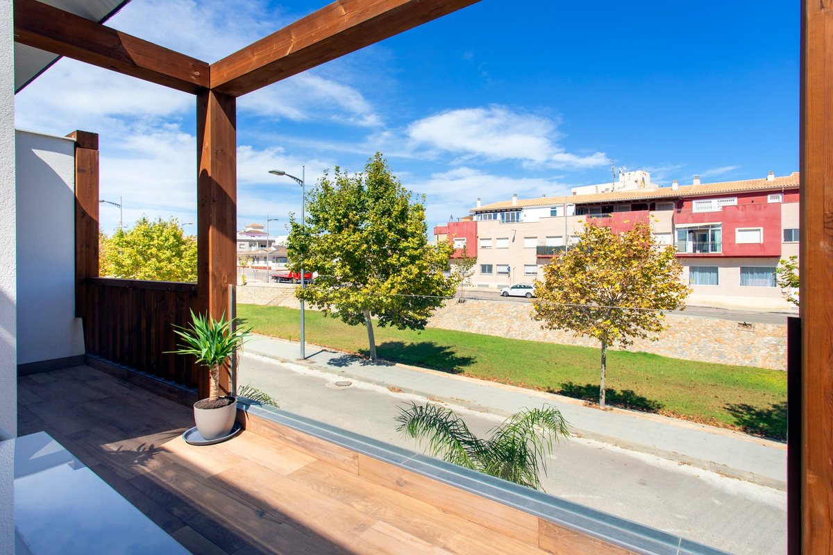 View from the balcony over a quiet tree-lined street and a grass strip in Pilar de la Horadada